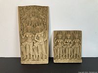 Two sandstone carvings side by side showing detailed relief figures in traditional attire.