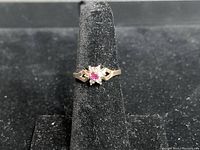 Front view of the 10KT gold ring showing the central ruby surrounded by diamonds in a cluster floral setting, held by prongs.