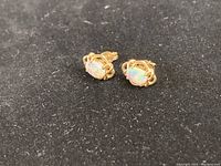 Front view of both earrings showing oval opals and gold settings