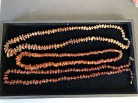 Three amber necklaces arranged on a flat surface showing the overall length and bead distribution.