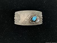 Front view of Navajo silver money clip showing stamped decorative elements and turquoise stone mounted with silver scrollwork.