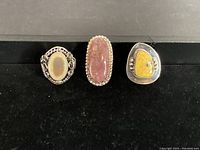 Three silver rings displayed side by side showing different stone inlays