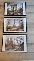 Three framed Paris art prints stacked showing landmarks: Arc de Triomphe, Eiffel Tower, Notre-Dame