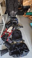 Overview of six backpacks arranged on floor and protective rain cover on hanger in background