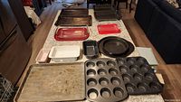 Overview of all baking trays, muffin pans, glass dishes, and small bakeware laid out on countertop.