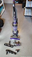 Front view of upright vacuum with floor head and laid out accessories