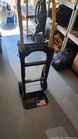 Front full view of the black hand truck dolly standing upright with yellow adjustable handle visible.