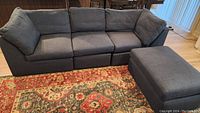 Front view of assembled sofa set: three modules and ottoman on patterned rug