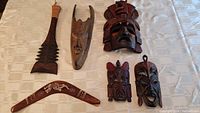 Lot arranged on table with all wood masks, Samoan war club, and boomerang clearly visible.