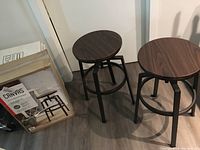 Two assembled Canvas Turner bar stools with dark brown wood seats and metal legs on hardwood floor.