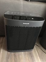 Front view of black Honeywell air purifier showing grille and brand name on front.