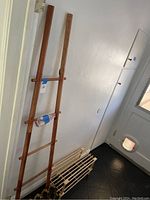 Wooden dark-stained blanket ladder standing upright against a wall with several horizontal rungs.