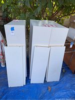 Three white bookcase units stacked outdoors, showing the exterior and sides with some discoloration and wear.