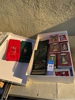 Box containing six Hallmark Keepsake ornaments and four holiday guest towels.