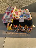 Photo of Christmas-themed bathroom linens (rug, shower curtain, hand towels) with colorful ornament prints, and Schmid Snow White and Seven Dwarfs collectible ornaments arranged together.