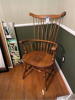 Full view of vintage wooden armchair placed in room corner showing spindle back, armrests, seat, and legs.