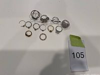 Top-down view of eleven assorted rings on white surface