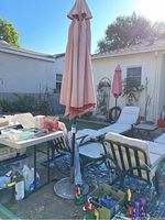 Closed larger patio outdoor umbrella with stand next to outdoor seating and tables