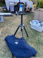 Full view of Gitzo tripod standing fully extended on grass with Bogen padded bag at base