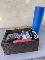 Woven basket containing workout DVDs, yoga strap, yoga block, and yoga mats visible outside the basket