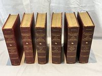 Front view showing six volumes standing upright with gilt embossed spines and brown leather covers.