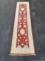 Full view of rug showing red field, cream border, and fringe