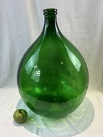 Front view with green apple for size reference, showing the large bulbous shape and green color of the jar.