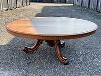 Full view of round tabletop and splayed pedestal base on gravel ground