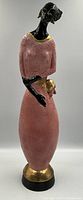 Full front view of signed sculpture showing the lady in pink with gold accents and black skin tone.