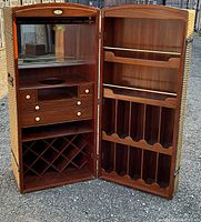 Opened bar cabinet showing interior compartments, mirror, drawers, and wine rack