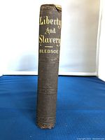 Photo of book spine showing embossed title and author in gold on textured dark cloth cover.