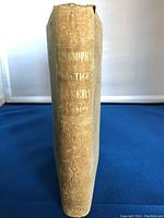 View of the book spine showing embossed patterns and faded gold lettering on a light cloth cover.