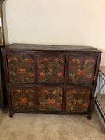 Front view of the antique wooden cabinet showing six hand-painted floral and vase design panels on door fronts.