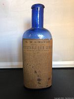 Front view of cobalt blue glass bottle showing original paper label for G.W. Simonds' Vegetable Pain Curer.