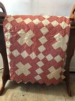 Full view of the quilt showing the overall patchwork pattern with large white crosses on a red background and scalloped edges.
