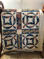 Full view of quilt draped over wooden rack showing overall ring block pattern