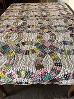 Full view of the quilt showing the Double Wedding Ring pattern and various multicolored fabric patches on white background.