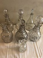 Group photo of all six glass decanters and one small cruet showing different shapes and stoppers.