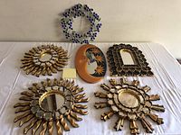 Full view of all five decorative mirrors displayed on white cloth background