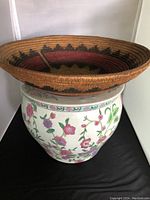 Woven basket placed atop ceramic planter displaying both items