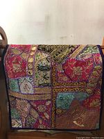Full view of vibrant Middle Eastern tapestry with multiple embroidered patches, beadwork, and mirrors