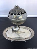 Side view of antique Turkish metal incense burner with cutout leaf lid and pomegranate top on round tray base
