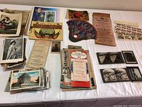 Wide overview of assorted vintage postcards, book, theatrical programs and glass negatives laid out on a flat white surface