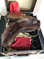 Overview of vintage accessories including mink fur collar, red beaded clutch, and wristlet clutches in a box