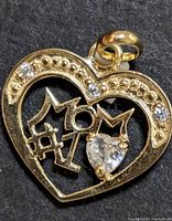 Close-up image of the 10K gold heart pendant, front-facing showing '#1 MOM' text and stones.