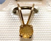 Close-up view of the 14K gold pendant with round citrine gemstone in four-prong setting.