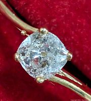 Close-up front view of round brilliant diamond set in 10K yellow gold bypass band