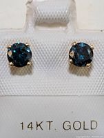 Front view of both blue diamond stud earrings on white card labeled ‘14KT. GOLD’