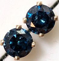 Close-up of single round blue diamond in four-prong 14K yellow gold setting