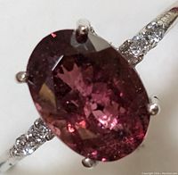 Close-up of oval pink tourmaline center and diamond-accented band.